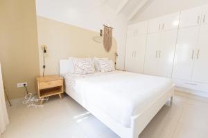 1 dormitorio blanco con 1 cama blanca grande y armarios blancos en Dushi Townhouse Curaçao en Willemstad