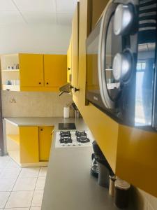 a kitchen with yellow cabinets and a stove at O’Rythme du KA in Pointe-à-Pitre