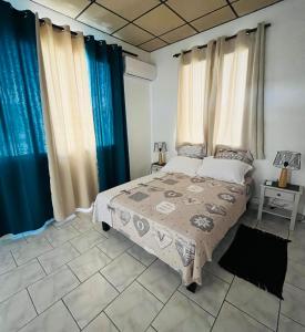 a bedroom with a bed and blue curtains at O’Rythme du KA in Pointe-à-Pitre