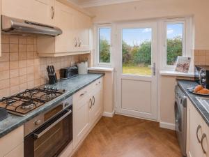 a kitchen with a stove top oven next to a window at Watch Cottage - Uk6729 in Lydstep