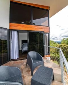 Habitación con balcón con cama y sillas. en Casa de montaña Arisa, en Cartago