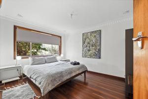 a bedroom with a bed and a large window at Valley House in Margaret River Town