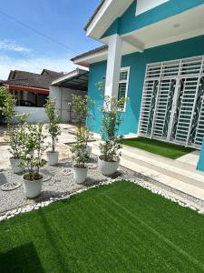 une maison avec quatre plantes en pot devant elle dans l'établissement Casa De Rose KUBANG KERIAN, à Kota Bharu