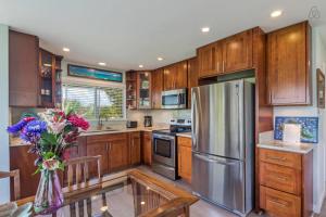a kitchen with wooden cabinets and a stainless steel refrigerator at Island Style Homebase 2 bedroom 1 bath AC full kitchen WasherDryer in Kailua
