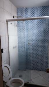 a bathroom with a toilet and a blue tiled shower at Grande Hotel in Duque de Caxias