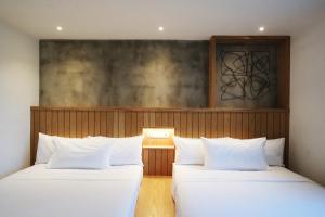 two beds with white pillows in a room at The Bayou Hotel Langkawi in Pantai Cenang