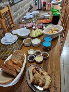 una mesa de madera con pan y otros alimentos. en KARAPOTÓ parador rural, en Cambará