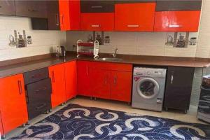 - une cuisine avec des placards rouges et un lave-linge dans l'établissement Amazing 5 Bedroom Holiday house, à ‘Ezbet `Abd el-Ḥamîd