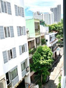 un edificio de apartamentos con un árbol delante de él en Luu Gia Hotel en Nha Trang