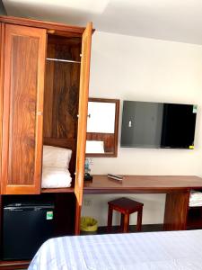 a bedroom with a bed and a desk with a tv at Luu Gia Hotel in Nha Trang