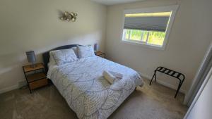 1 dormitorio con 1 cama con edredón blanco y ventana en Avo-Sa Orchard, en Lake Country