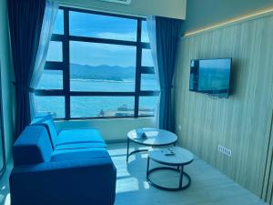 a living room with a blue couch and a large window at JQ Jesselton Quay Homestay Near Suria Mall, Gaya Street, jetty by GoodTravelKK 善旅民宿 in Kota Kinabalu