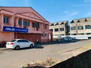 een witte auto geparkeerd voor een roze gebouw bij Season Inn Langkawi Motel in Kuah