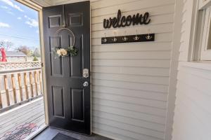 une porte noire avec un panneau de bienvenue sur une maison dans l'établissement Downtown 1 Bedroom Charmer - Walk, Bike, Enjoy!!, à Rapid City