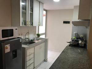 una pequeña cocina con fregadero y microondas en 595 Departamento en Chorrillos en Lima