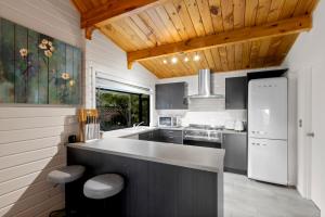 a kitchen with a white refrigerator and a stove at Kereru Cottage, Romantic & Beautiful Log Cabin - Queenstown in Queenstown