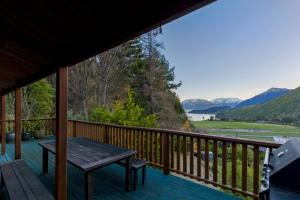 a deck with a table and a view of the mountains at Kereru Cottage, Romantic & Beautiful Log Cabin - Queenstown in Queenstown