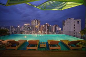 a large swimming pool with chairs and a city skyline at Seaesta Nha Trang Hotel in Nha Trang