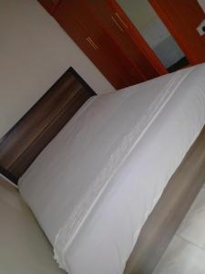a bed with white sheets and a wooden headboard at Tranquil Homes in Nanyuki