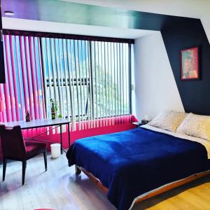 1 dormitorio con cama, escritorio y ventana grande en Casa Maguey, en Ciudad de México