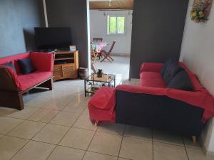 sala de estar con 2 sofás rojos y TV en Villa letchi, en Entre-Deux
