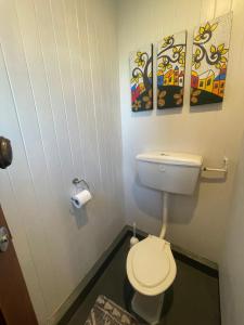 a bathroom with a toilet and two paintings on the wall at Big Fully Equipped 3BRM Quiet Farm House Near Beach & 12 min to Town in Riverton