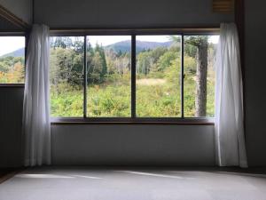 a room with a window with a view of a field at 大自然の一軒家。便利社会からの逃避、究極のセルフ山小屋ライフ in Madarao Kogen