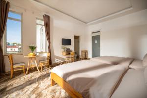 a white bedroom with a bed and a table and chairs at Raon Dalat - STAY 24H in Da Lat