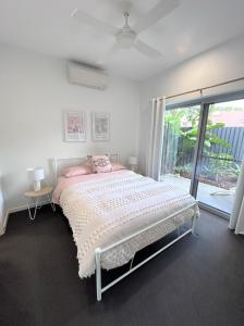 a white bedroom with a bed and a window at Unit 1 - Manly Boutique Apartments in Brisbane