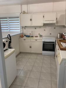 a kitchen with white cabinets and a tile floor at Chai Saint Jean CAMELIA Piscine et SPA in Saint-Jean-de-Boiseau