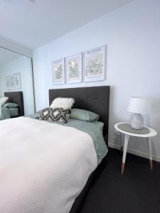 Un dormitorio con una gran cama blanca y una mesa en Unit 2 - Manly Boutique Apartments en Brisbane