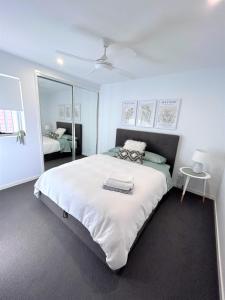 um quarto com uma grande cama branca e um espelho em Unit 2 - Manly Boutique Apartments em Brisbane