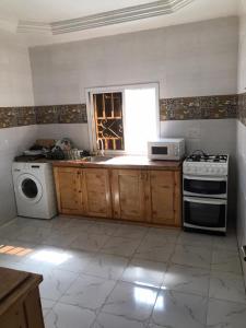 uma cozinha com um lavatório e um fogão forno superior em Marie's residence em Medina Suware Kunda