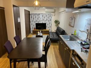 eine Küche und ein Wohnzimmer mit einem Tisch und Stühlen in der Unterkunft ケイアイコンホテルズ 池下 in Chikusachō
