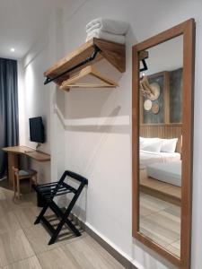 a mirror in a room with a bed and a chair at The Bayou Hotel Langkawi in Pantai Cenang
