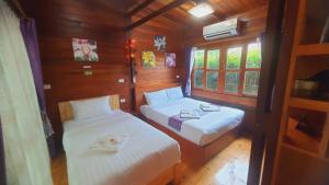Cette petite chambre comprend 2 lits et une fenêtre. dans l'établissement Areeya phubeach resort wooden house, à Ban Chong Phli