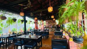 um restaurante com mesas e cadeiras e vasos de plantas em Residence Indochine Suite em Siem Reap