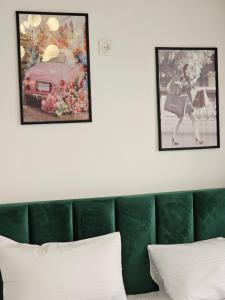 two pictures on the wall above a green couch at Boutique Hotel Honey in Kutaisi