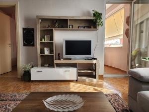 a living room with a tv and a couch at Cozy sunlit apartment with scenic balcony view in Tirana