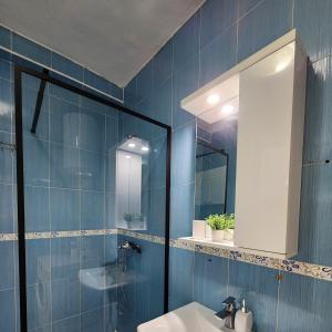a blue bathroom with a sink and a mirror at Cozy sunlit apartment with scenic balcony view in Tirana