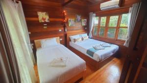 two beds in a room with wooden walls and windows at Areeya phubeach resort wooden house Coliving Coworking in Ban Chong Phli +93 photos