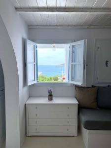 Habitación con banco y ventana con vistas al océano en Blue Dolphin Antiparos Villas and Suites, en Agios Georgios