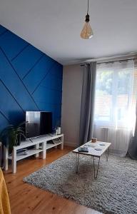 a living room with a blue wall and a tv at Villa Aubépine in La Bourboule