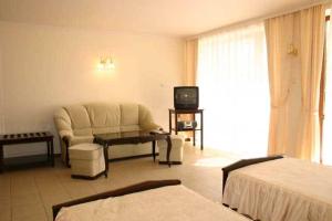 a hotel room with a couch and a tv at Hotel Klisura in Sunny Beach