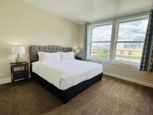 Un dormitorio con una cama grande y dos ventanas. en Downtown Digs-View of the City! Stay above local restaurants and nightlife, posh amenities heated toilet seat, oversized rain shower head in glass shower, in-unit laundry, one garage parking spot, en Boise