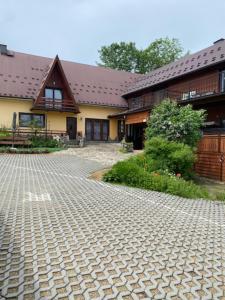 a house with a cobblestone driveway in front of a building at Domek Koniec Świata in Dzianisz
