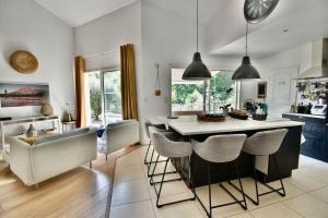 een keuken met een groot eiland met barkrukken bij La villa du Petit Bois in Lignan-de-Bordeaux