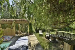 een achtertuin met een houten terras met een hangmat en een boom bij La villa du Petit Bois in Lignan-de-Bordeaux