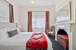 a bedroom with a bed with a red blanket and a fireplace at Stunning newly renovated home in perfect location in Hobart