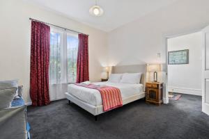 a bedroom with a bed and a large window at Stunning newly renovated home in perfect location in Hobart +8 photos